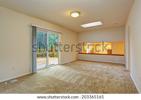 Bright soft ivory empty room with beige carpet floor and slide glass door to walkout deck
