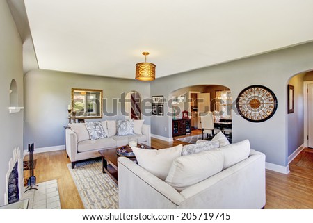 Light grey living rom with hardwood floor and rug. Furnished with white sofas and wooden coffee table