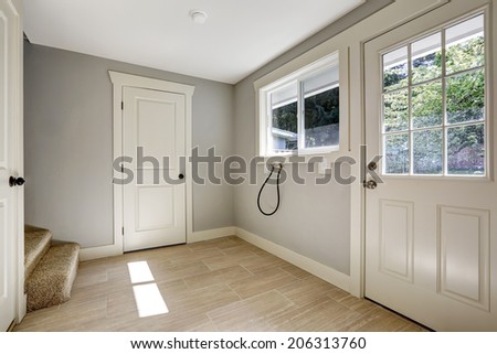 Empty light grey hallway with tile floor and white entrance door