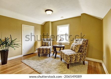 Bright yellow small room with two colorful chairs, small round table and beige rug on hardwood floor