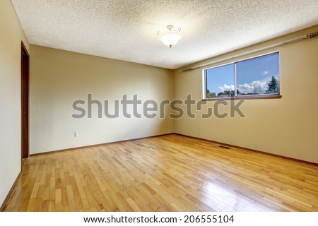 Empty bedroom in soft ivory with one window and hardwood floor