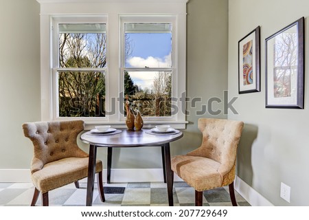 Small dining area in kitchen room. View of served round table with brown chairs