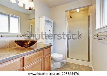 Bathroom interior with glass door shower, wooden vanity with vessel sink and white storage cabinet
