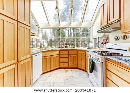 Bright kitchen room with glass wall and ceiling in countryside house.
