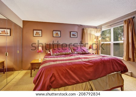 Bedroom interior with beautiful bed in red and mocha and mirror door closet