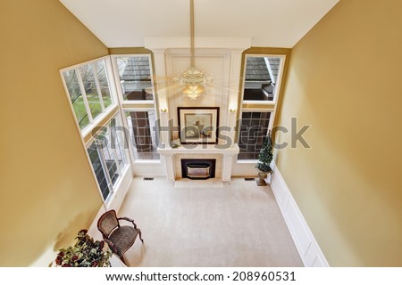 Empty living room interior in luxury house with french windows and fireplace. Panoramic view from upstairs hallway