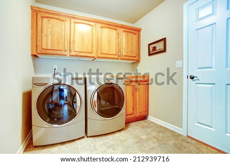 Laundry room with modern appliances and light tone cabinets