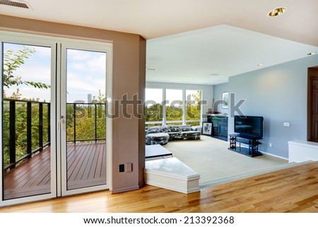 Bright house interior. Living room with large window and hallway with door to walkout deck