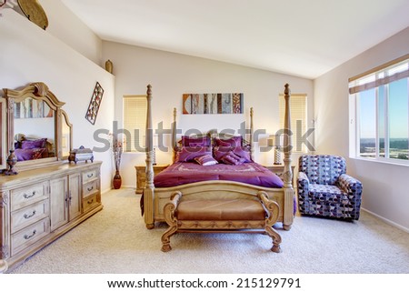 Luxury bedroom with high pole carved wood bed, bright purple bedding and vanity cabinet