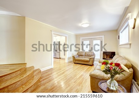 Very bright room with leather couches and fresh flowers on the table. Light brown hardwood floor blend with leather couches