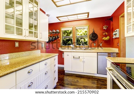 Kitchen room with bright red wall and white cabinets with granite tops