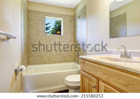Empty bathroom with tile wall trim, small window and wooden vanity cabinet with mirror