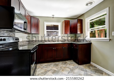 Kitchen with bright burgundy cabinets and black appliances.