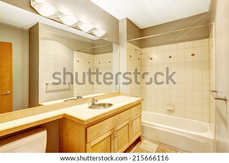 Empty bathroom with large mirror and tile wall trim