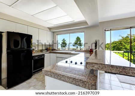 White kitchen room with black appliances and granite tops.  Kitchen with walkout deck