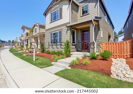 Two story house exterior. Entrance porch with red wooden door and curb appeal
