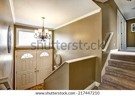Entrance hallway with mustard color walls and white door. View from staircase