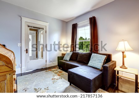 Light lavender room interior with brown couch, wooden table with lamp and floral rug