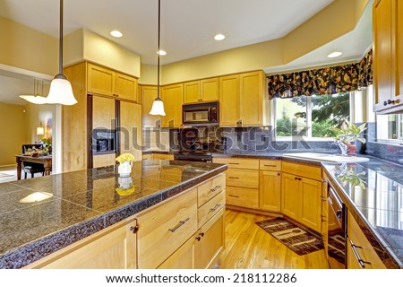 Kitchen room with backsplash trim, granite tops and black appliances