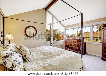 Bedroom with high iron frame bed and vaulted ceiling.