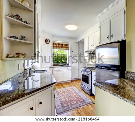 Kitchen area with white cabinets, granite tops and steel refrigerator