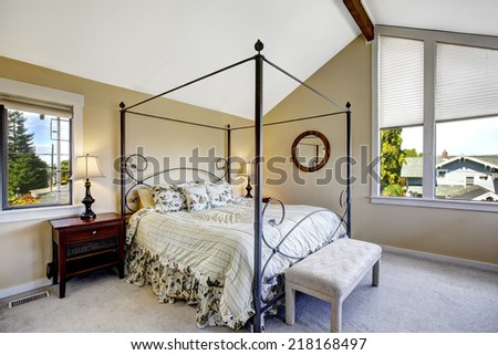 Bedroom with high iron frame bed and vaulted ceiling