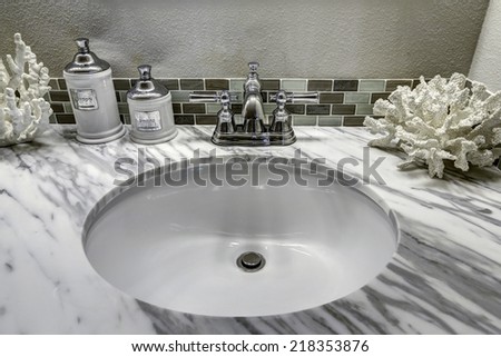 Modern bathroom vanity cabinet with white granite top. Sink view. White sink with steel faucet and decorated corals