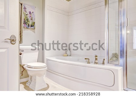White bath tub with tile trim and white toilet