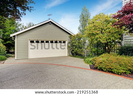 Garage with concrete driveway with trees alongside