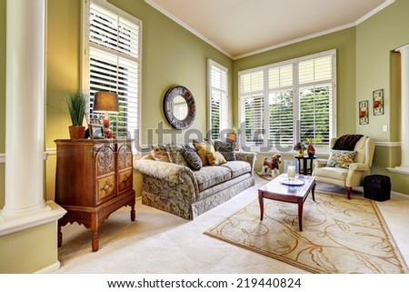Bright green room with antique carved wood cabinet, floral sofa and coffee table