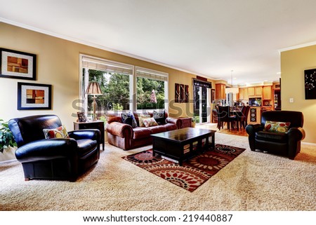Luxury family room with rich leather couch and armchair .