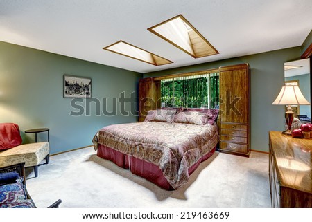 Luxury bedroom interior with burgundy bed and storage combination. Vanity cabinet with lamp
