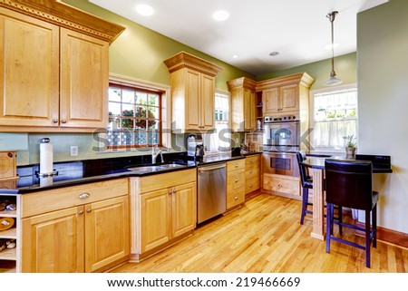 Light green tone kitchen with wooden cabinets and small table with chairs.