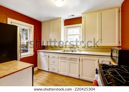White kitchen cabinets with bright red wall in old house
