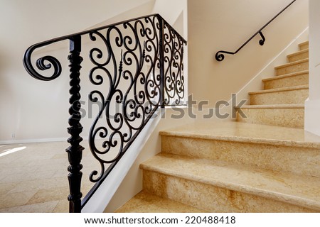 Empty house interior with shiny tile floor. Marble staircase with black wrought iron railing