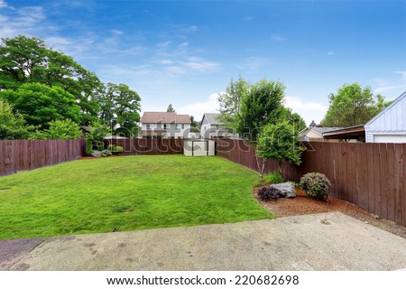 Spacious backyard area with  dark brown wooden fence and shed. View from patio area
