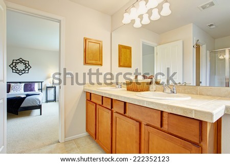 Bathroom with honey tone vanity cabinet and large mirror. Exit to master bedroom
