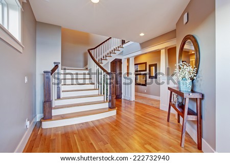 Bright hallway with wooden staircase. Staircase with white railings and brown trim