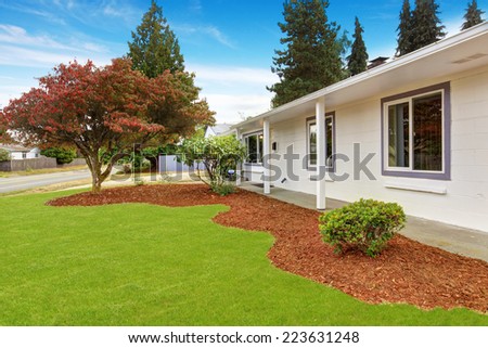 Simple house exterior in white color. Front yard landscape with sawdust and lawn.
