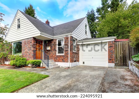 Cozy house with brick trim. Entrance porch with bright orange door and staircase