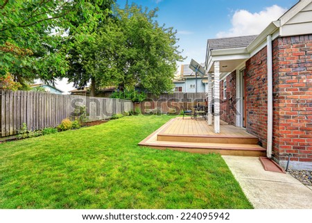 Brick house exterior with walkout wooden deck and green lawn