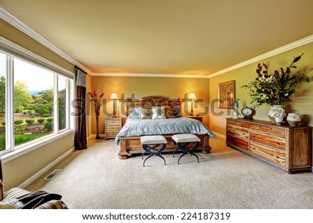 Spacious luxury bedroom with carved wood bed, nightstands and dresser decorated with flowers