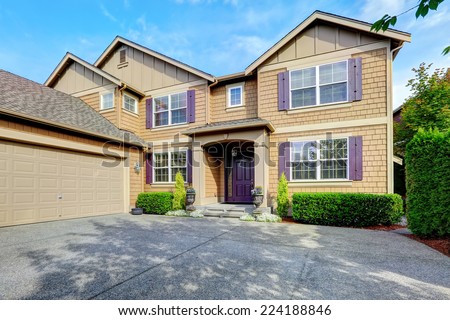 Luxury house. Clapboard siding exterior with purple elements. Entrance porch with trimmed hedges along the walls and garage with driveway