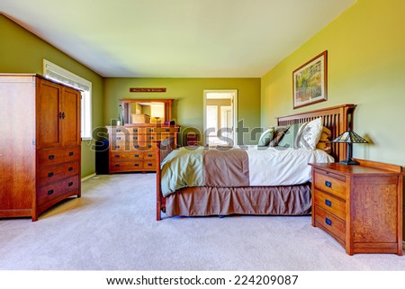 Master bedroom interior in bright green color with wooden bed, nightstand, bedroom vanity cabinet and wardrobe.