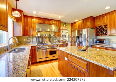 Shiny luxury kitchen room with island, granite tops, steel refrigerator, dishwasher, stove and hood