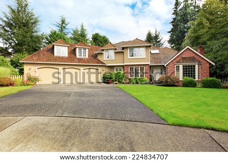Luxury house exterior with brick trim, tile roof and french windows. House with three car garage