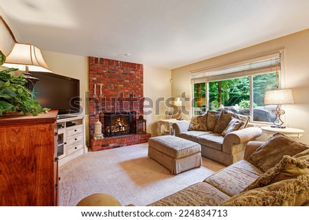 Bright ivory living room with brick background fireplace and comfortable couch with tv