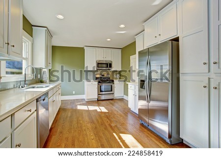 Green kitchen room with white storage combination, steel stainless appliances and hardwood floor