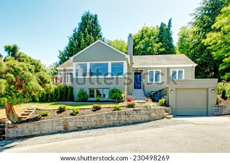 House exterior in clapboard siding. House with garage, driveway and front yard landscape