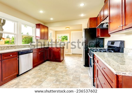 Bright kitchen room with black and steel appliances, beige tile floor and bright storage combination
